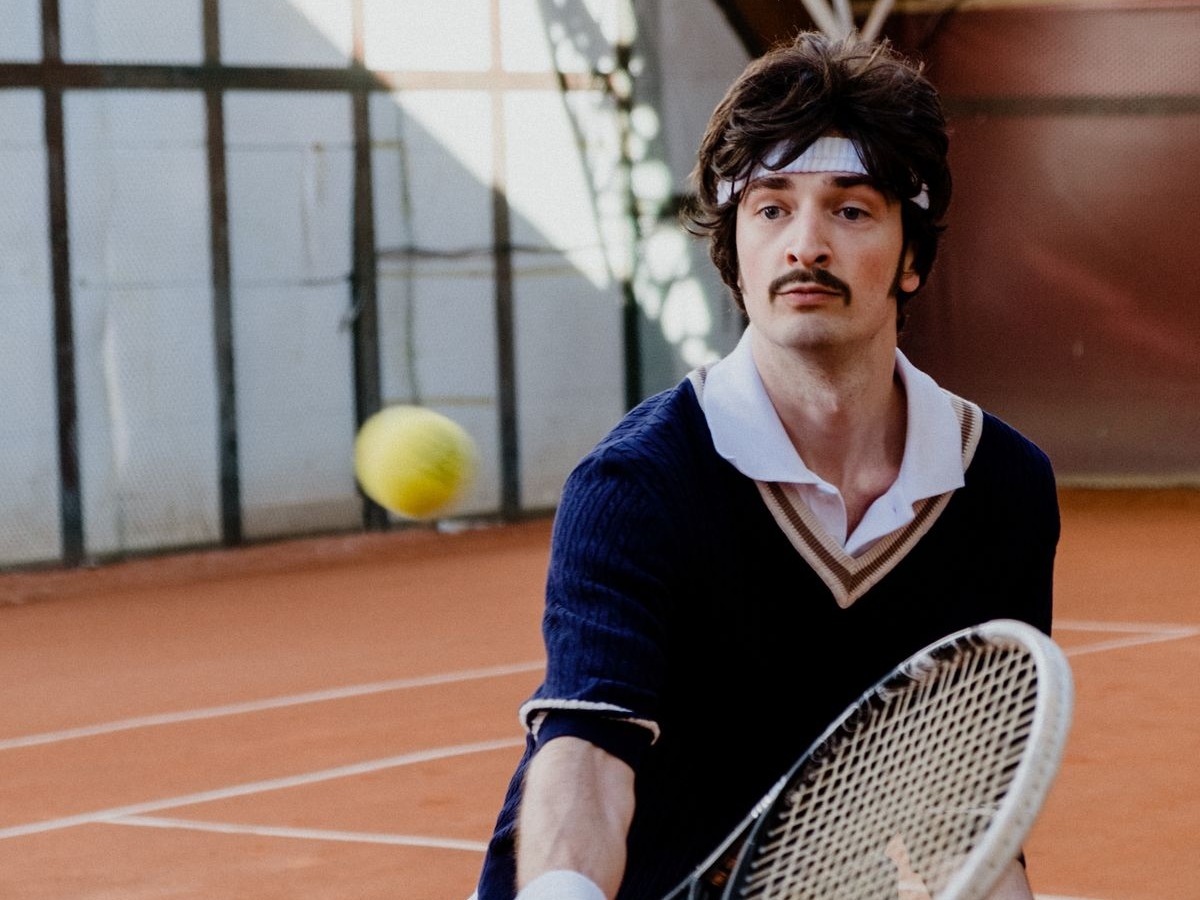 Tennis player hitting a forehand volley at the net on a clay court
